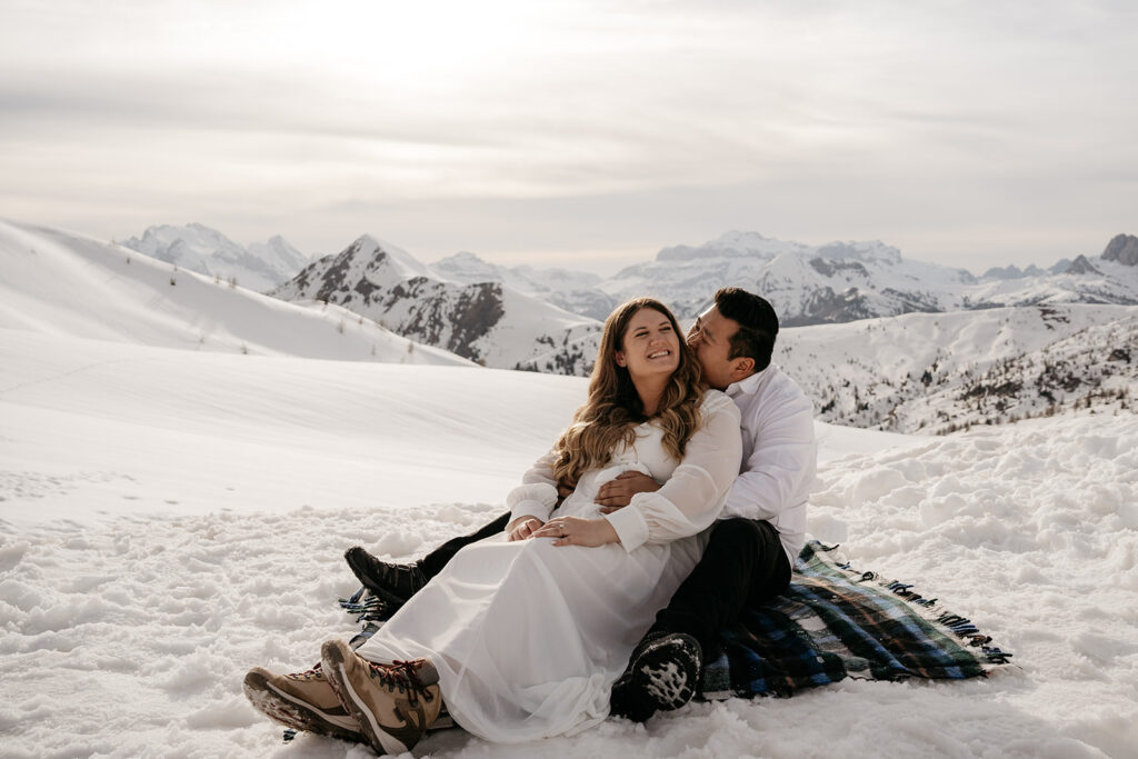 Couple sitting in snowy mountain landscape.