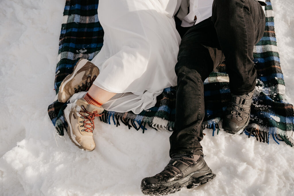 Couple sitting on blanket, snow-covered ground