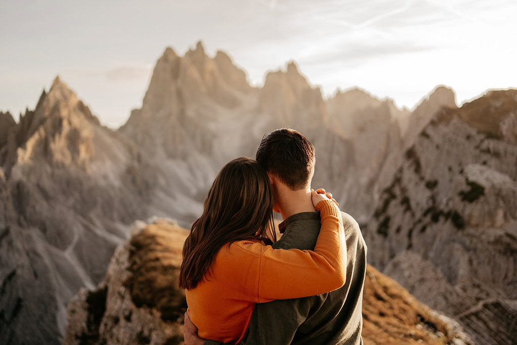 Couple hugging in mountain landscape at sunset.