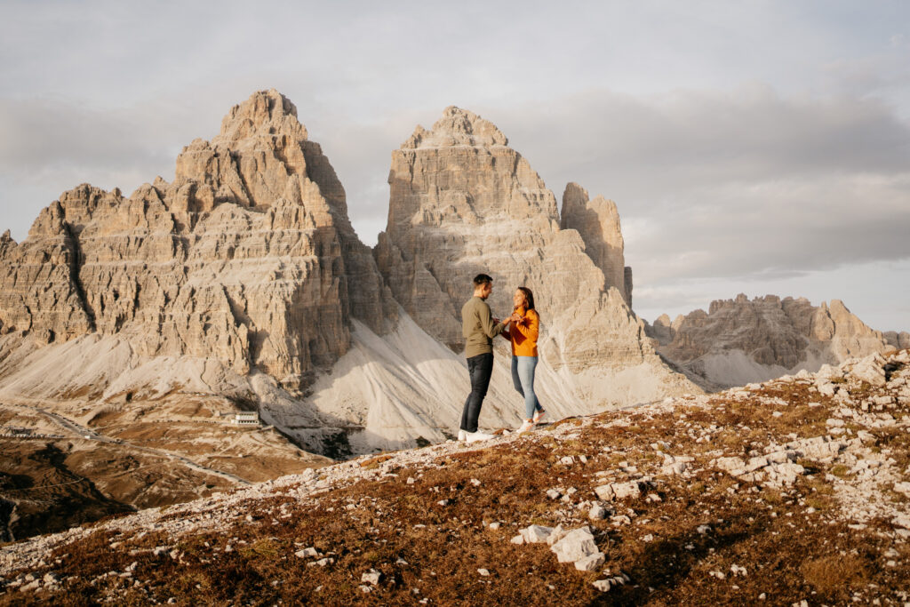 Couple standing in front of rugged mountain landscape.