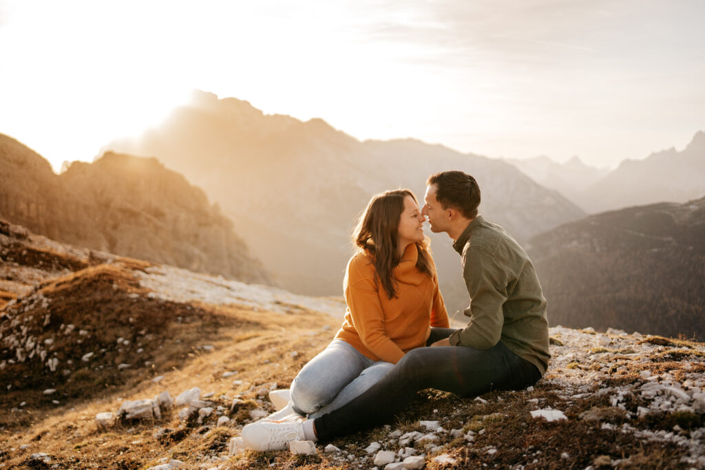 Couple sitting on mountainside at sunset.