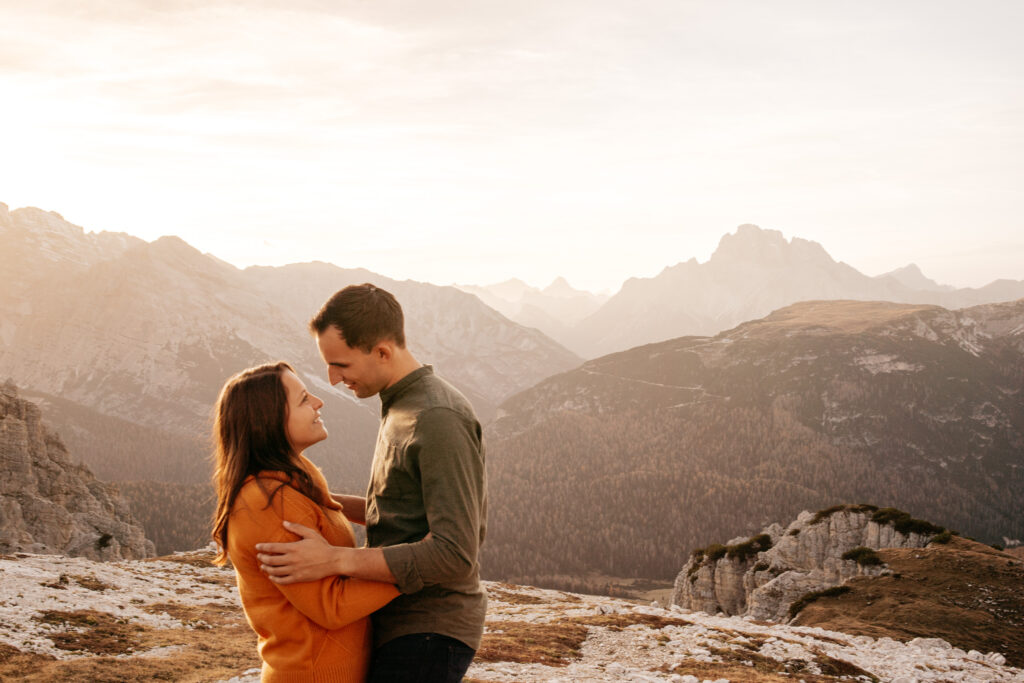 Couple embracing in mountainous landscape at sunset.