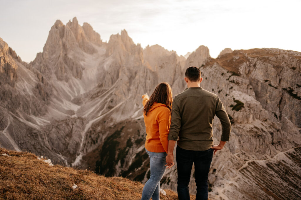 Couple admiring scenic mountain landscape at sunset.