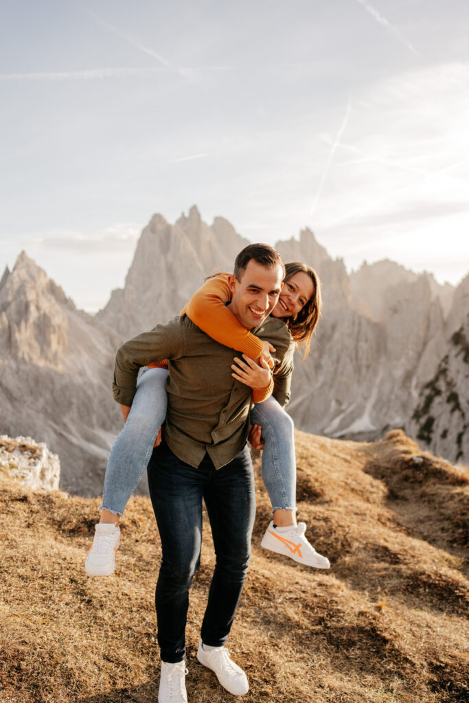 Couple piggybacking with mountain scenery background.