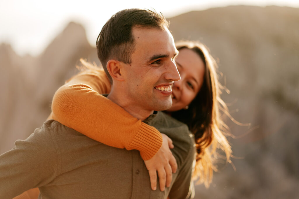 Smiling couple enjoying a piggyback ride outdoors.