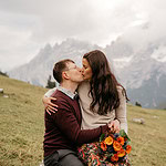 Couple kissing in a mountainous landscape with flowers.