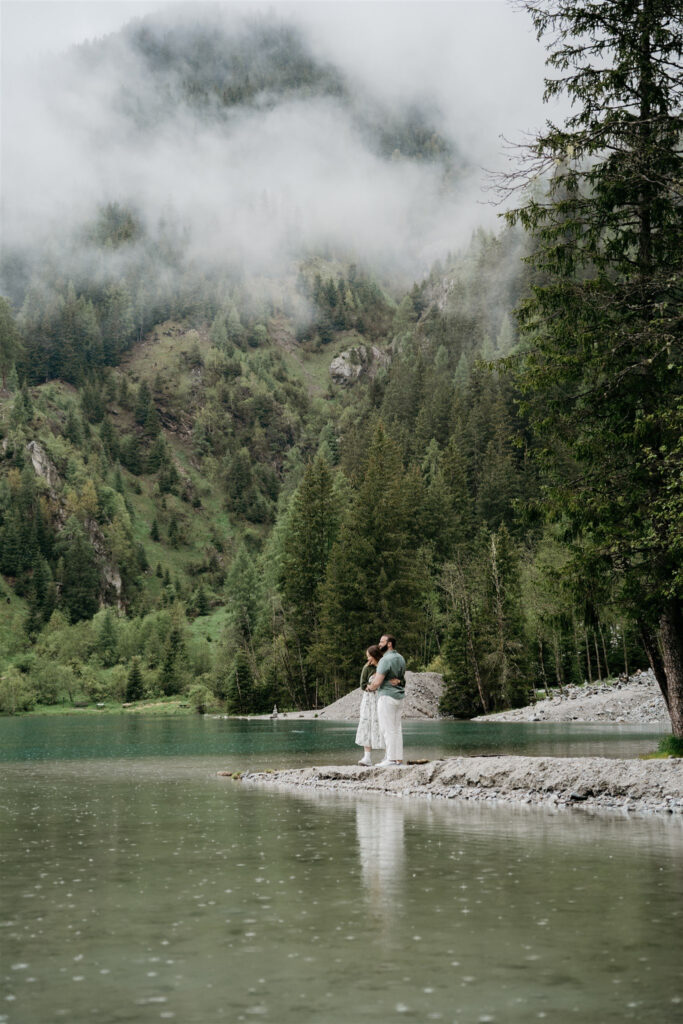 Couple embraces by misty forest lake.