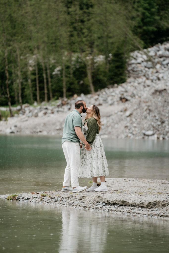 Couple kissing by a lake in nature.