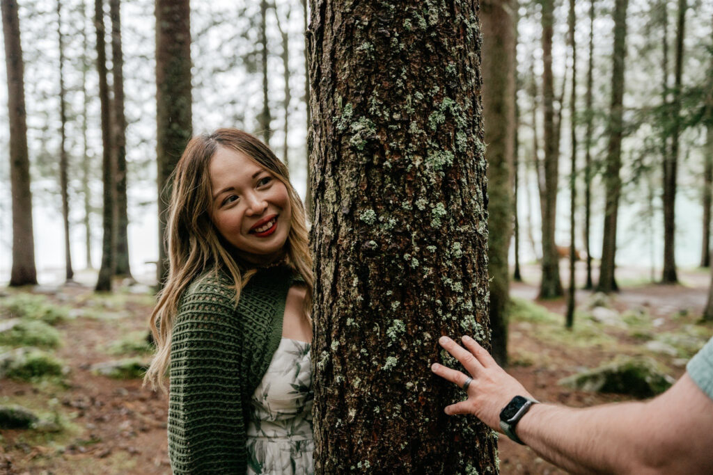 Smiling woman and hand touching tree in forest.