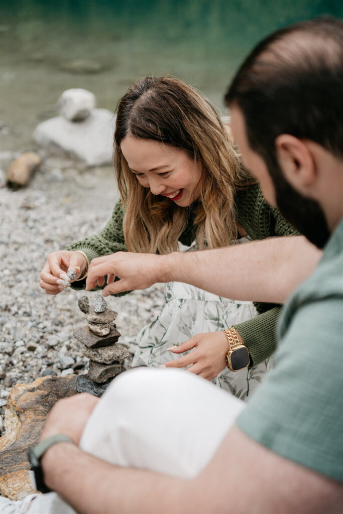 Two people stacking stones by lakeside