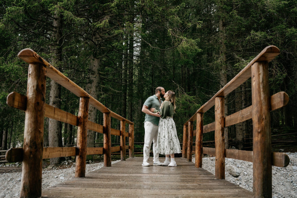 Couple kissing on a wooden bridge in forest.