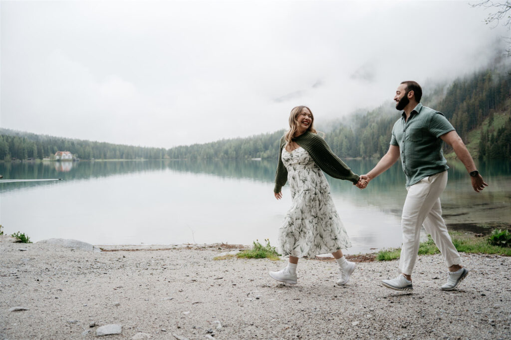 Couple happily walking by a misty lake.