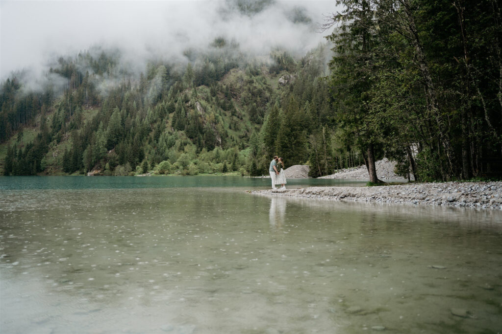 Couple embracing by misty lake and forest