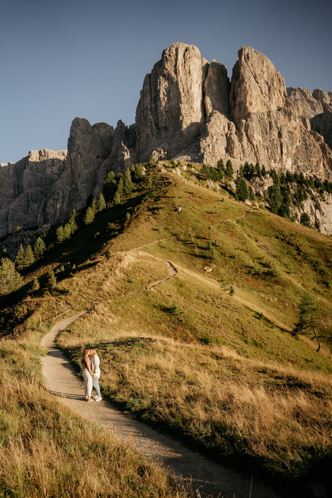 Couple embracing on mountain path in sunny landscape