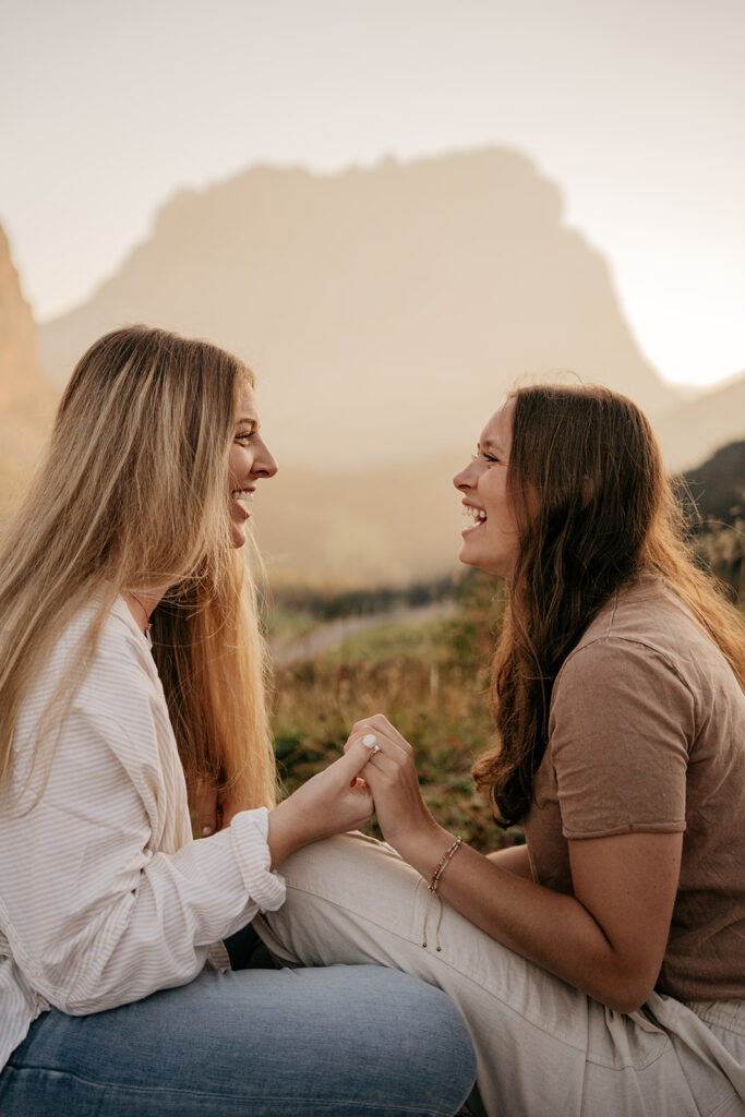 Two women laughing in a scenic outdoor setting.