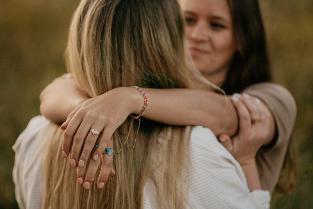 Two women hugging closely outdoors.