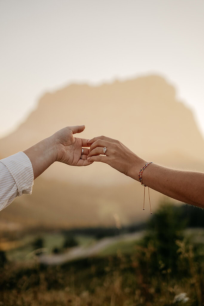 Hands reaching under sunset with mountain background