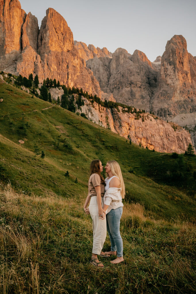 Two women embracing in mountain landscape at sunset.