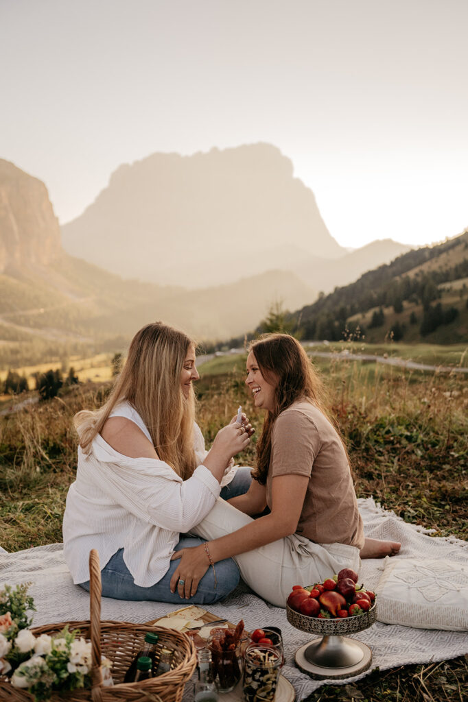 Couple enjoys mountain picnic with fruits and cheese.