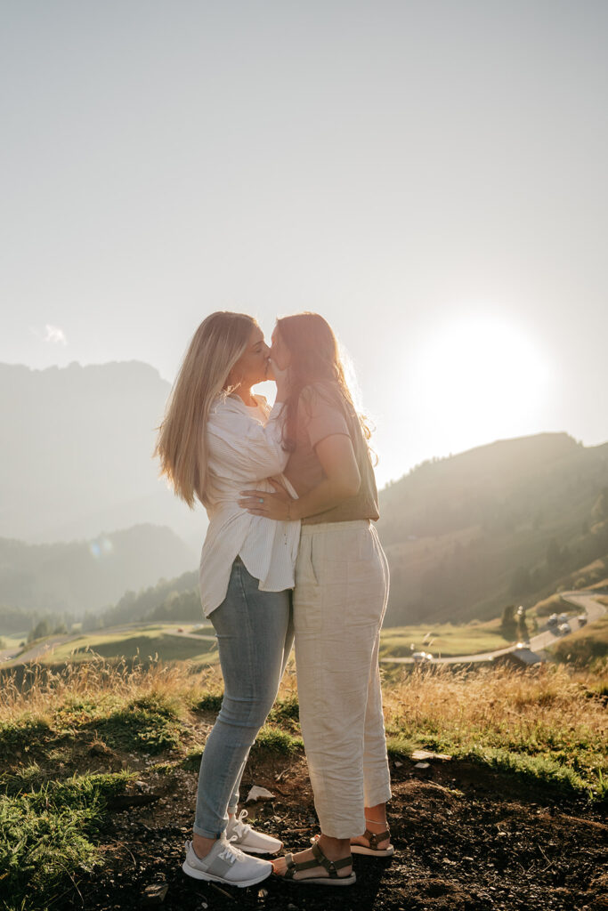 Couple kissing at sunset in scenic landscape.