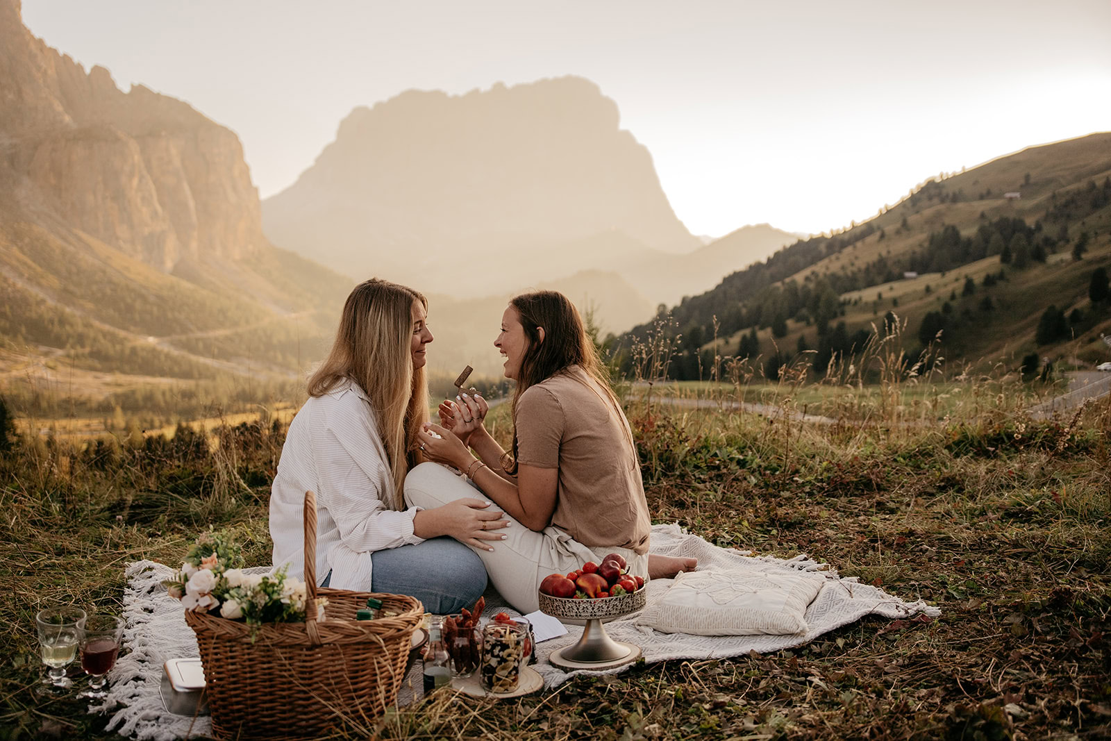 Couple enjoying picnic against mountain backdrop.