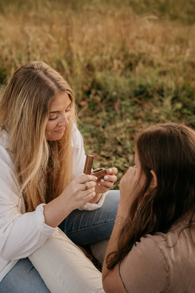 Two women holding a wooden box outdoors.