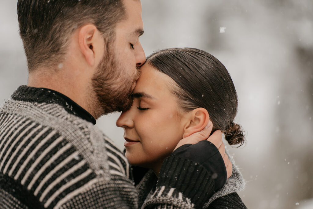 Couple embracing in snowy outdoor setting.