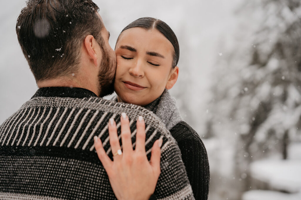 Couple embracing in snowy outdoor setting.