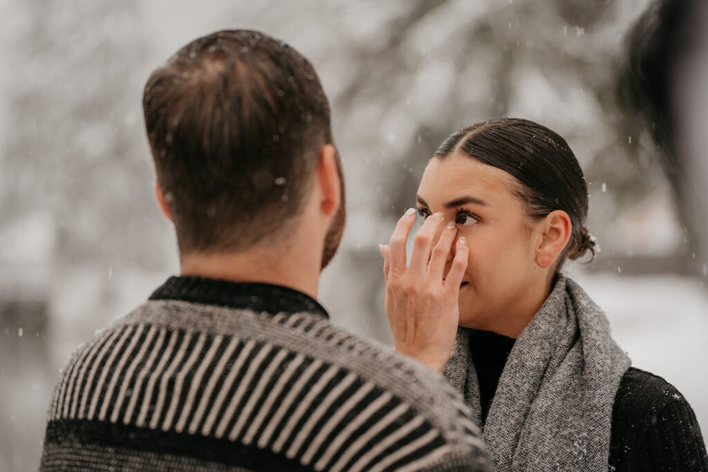 Woman wiping eye in snowy weather scene.