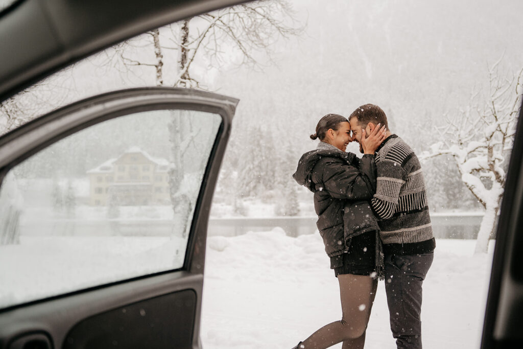 Couple embracing in snowy winter landscape.