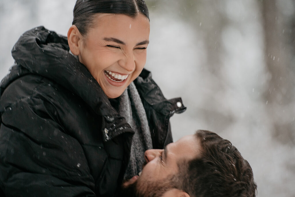 Couple laughing together in snowy outdoors.