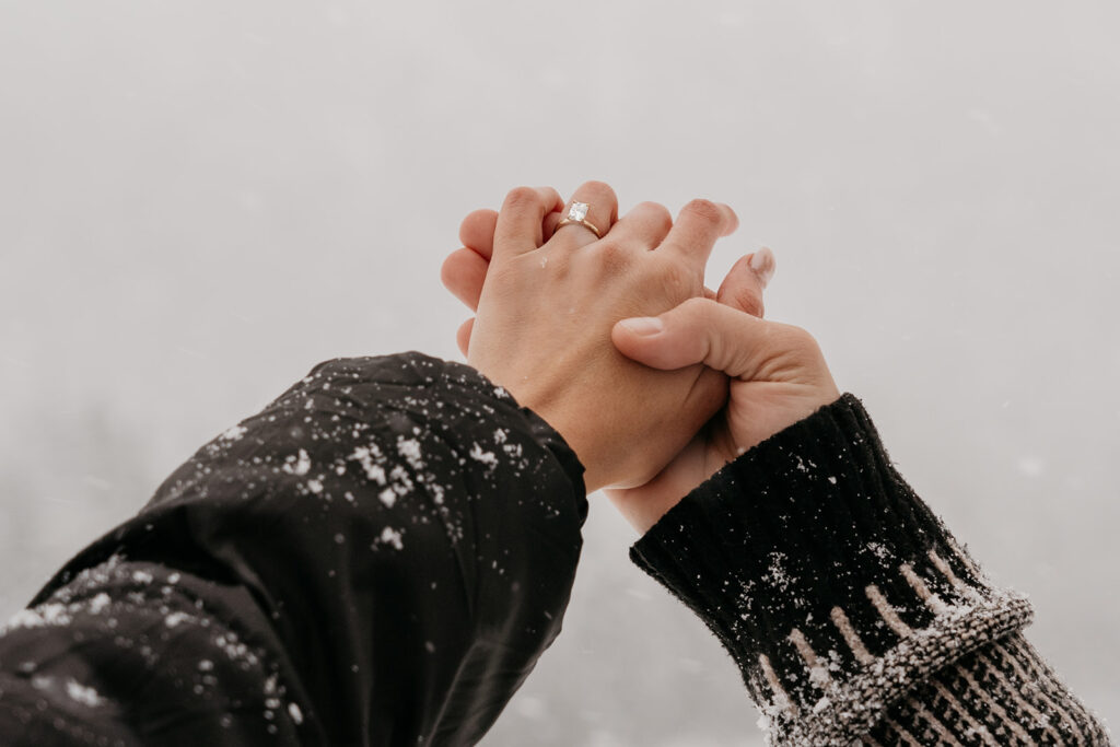 Couple holding hands in snowy winter scene.