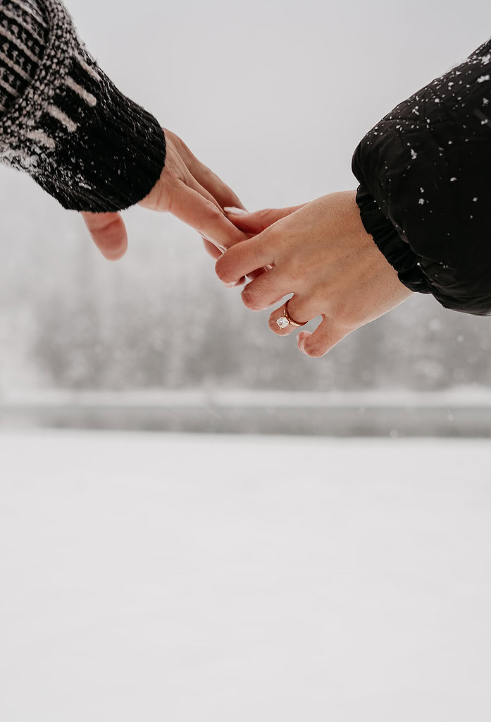 Couple holding hands on snowy day.