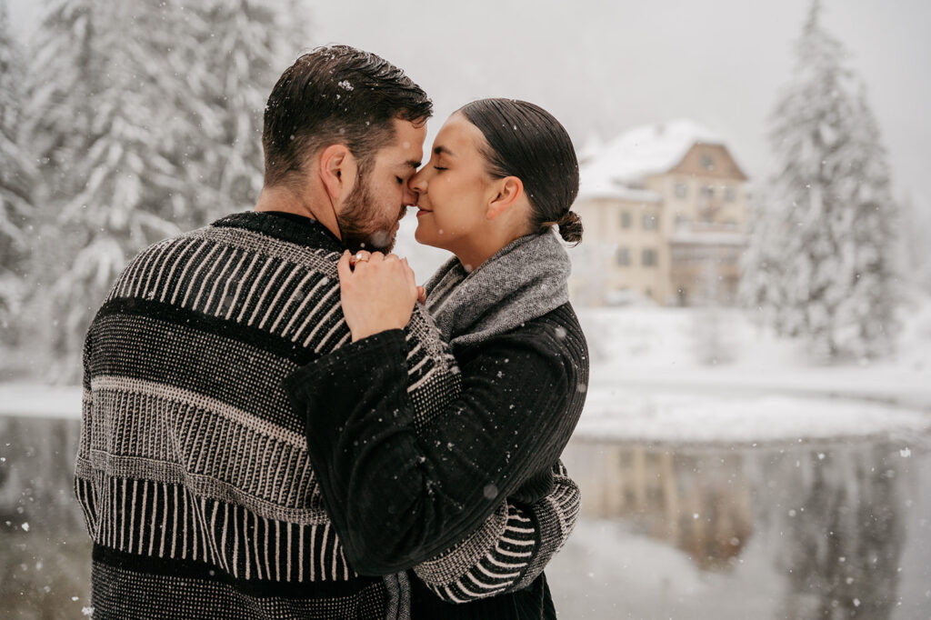 Couple embracing in snowy winter landscape.