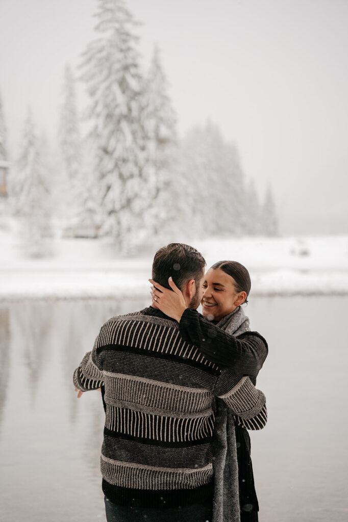 Couple embracing by a snowy lake.