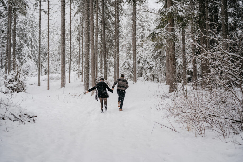 Couple walking in snowy forest holding hands