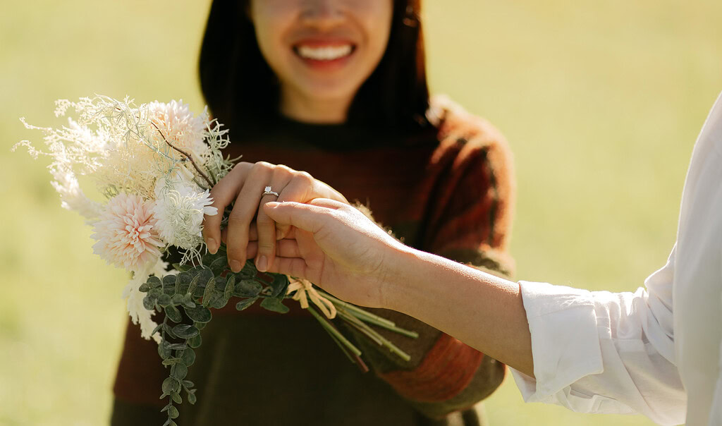 Person receives engagement ring with bouquet.