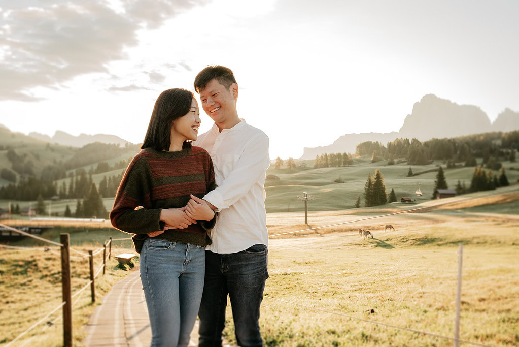 Couple smiling in scenic countryside landscape.