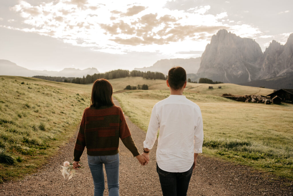 Couple holding hands in mountain landscape.