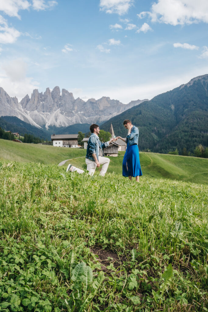 Marriage proposal in front of majestic mountain scenery.