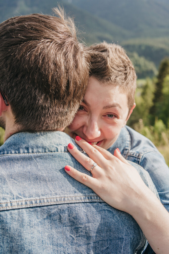 Couple embracing with engagement ring visible, joyful expression.