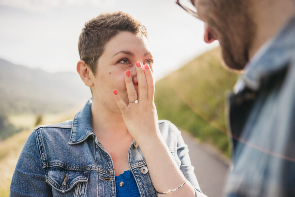 Surprised woman with engagement ring outdoors.