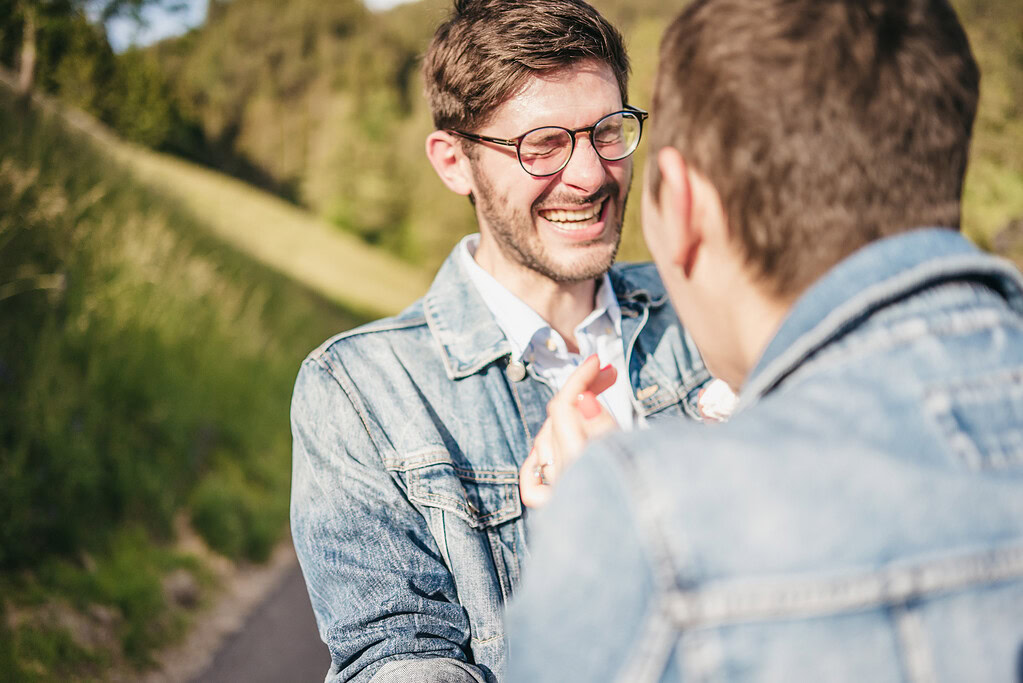 Two people laughing outdoors in denim jackets