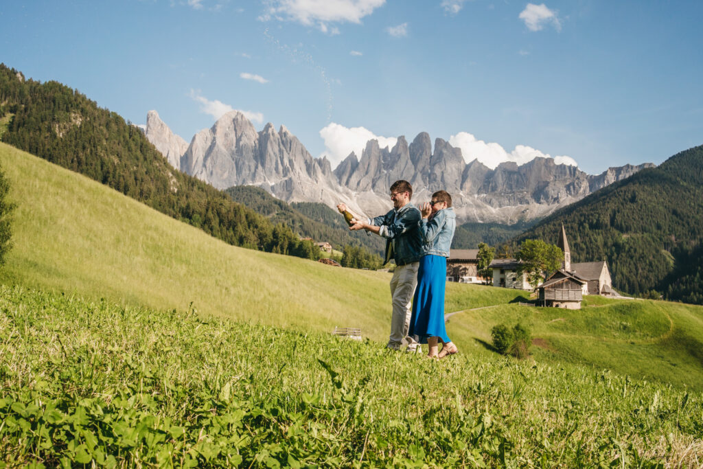 Couple celebrating with champagne in mountain meadow