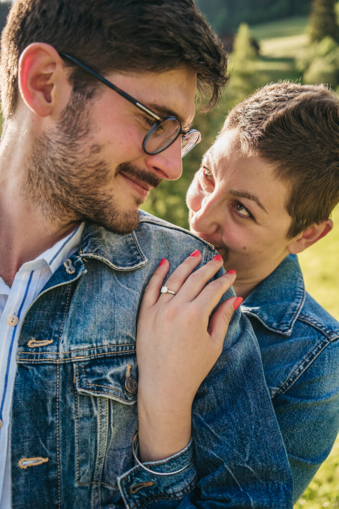 Couple in denim jackets, smiling outdoors.