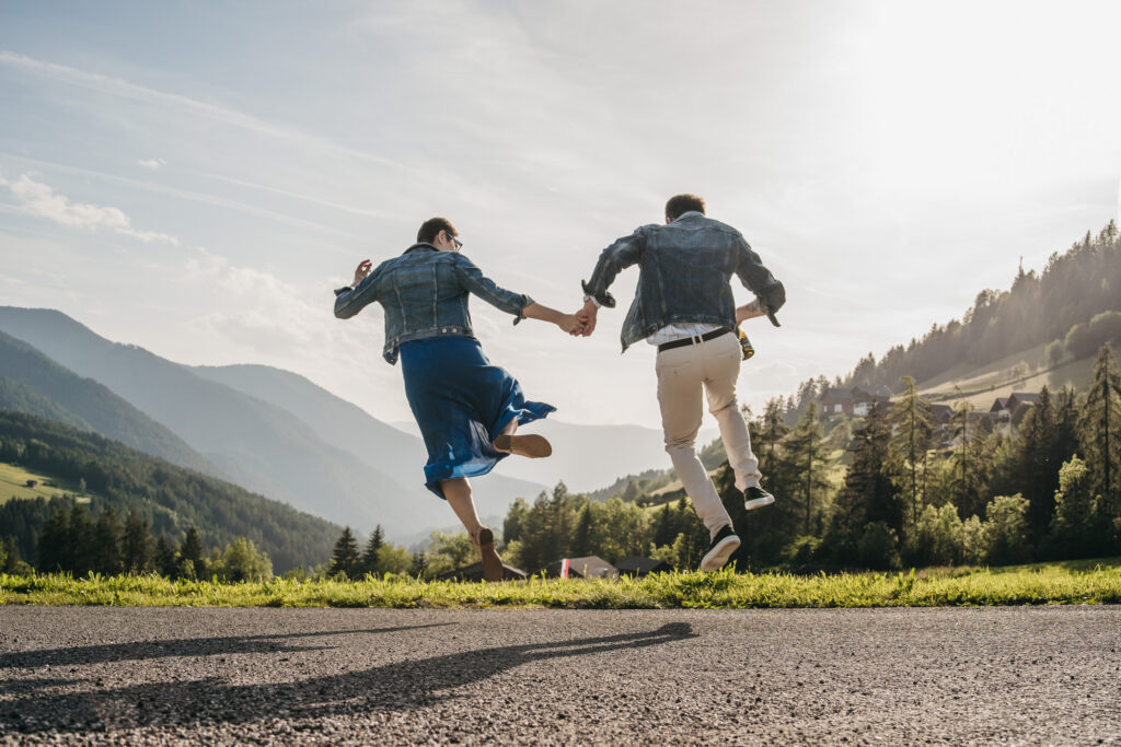 Couple jumping joyfully in scenic mountain landscape.