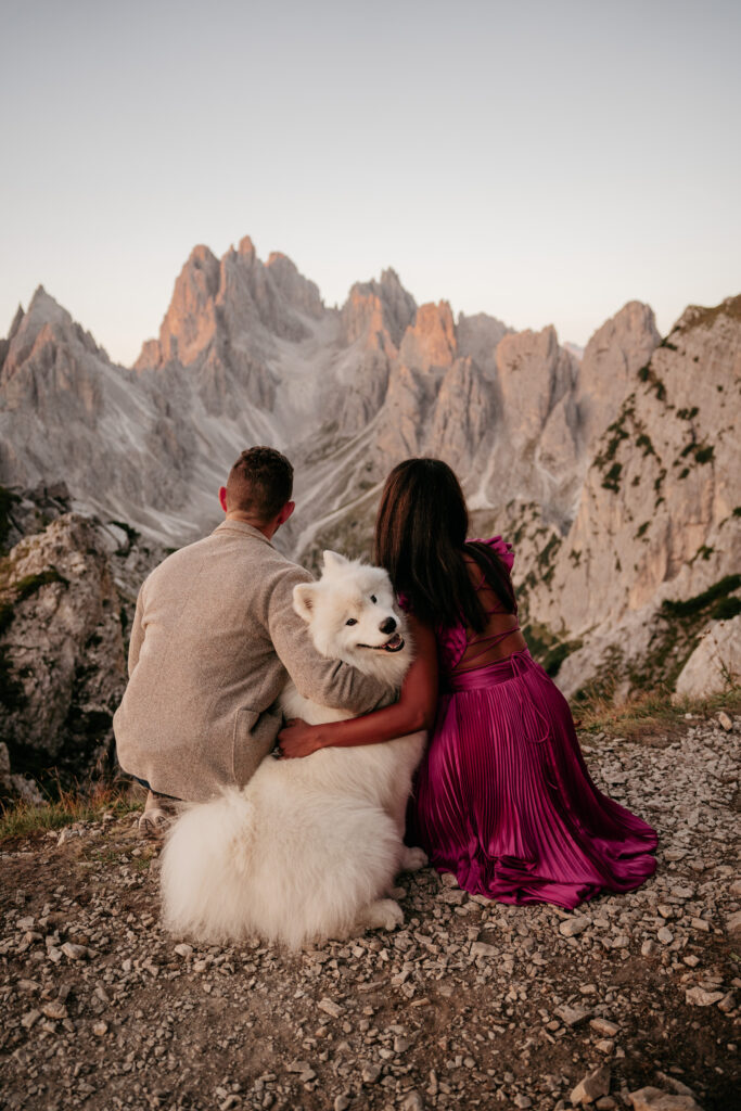 Couple with dog enjoying mountain sunset view.