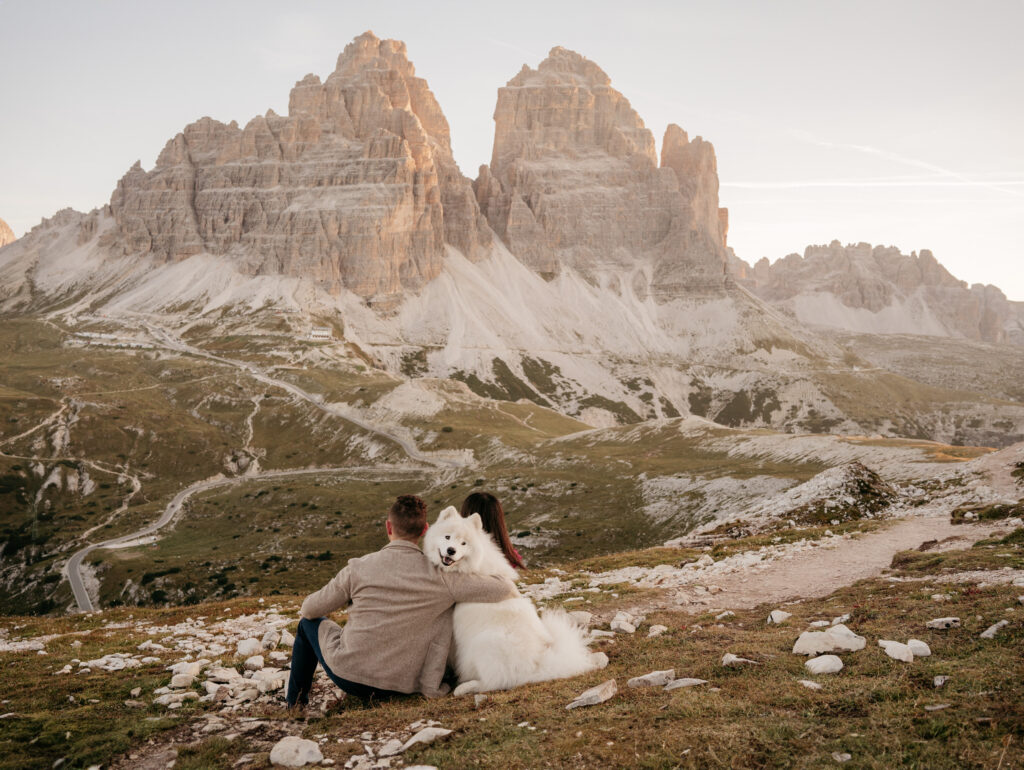 Couple with dog sitting by mountain view.