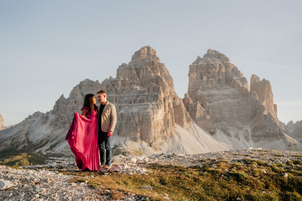 Couple standing near Dolomites mountains at sunset.