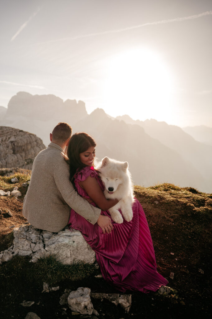 Couple with fluffy dog on mountain sunset